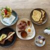 Breakfast assortment with omlettes, eggs, english breakfast, fruit salad and toasts with tomatoe and avocado and coffee