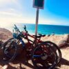 two bikes parked with beach in background on a sunny day
